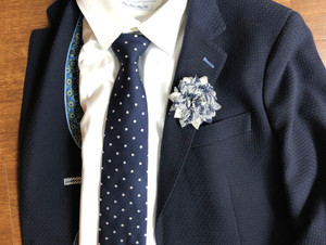 Blue and white floral lapel pin on blue jacket.